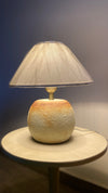 Small handcrafted lamp with caramel tones placed on modern shelf