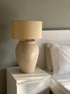 Elegant neutral-toned terracotta lamp placed on wooden sideboard