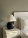 Black Orb terracotta lamp on a white bedside table in a small bedroom