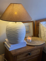 Elegant cream lamp placed on wooden table in neutral setting

